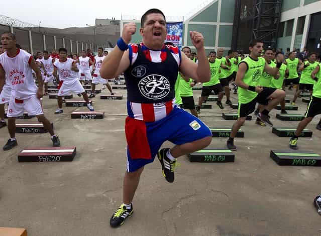 Inmates participate in a group workout at the Lurigancho prison on the outskirts of Lima, Peru, in an attempt to break the Guinness World Record for the largest group of prisoners working out at the same time, on June 14, 2013. (Photo by Martin Mejia/Associated Press)