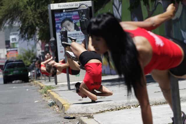 Women perform a pole dancing routine during the national day celebration of [Urban Pole] dance along a street in Monterrey, Mexico, on June 9, 2013. (Photo by Daniel Becerril/Reuters)
