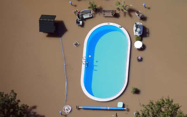 A garden with a swimming pool is inundated by the waters of the Elbe river during floods near Magdeburg in the federal state of Saxony Anhalt, Germany, June 10, 2013. (Photo by Thomas Peter/Reuters)