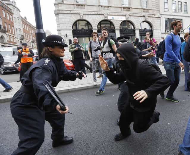 A protester demonstrating against the upcoming G8 summit tries to evade a police officer in central London June 11, 2013. Police in riot gear moved in on a building in London's Soho district where activists had planned an anti-G8 protest through the British capital on Tuesday, before next week's summit of world leaders in Enniskillen, Northern Ireland. (Photo by Luke Macgregor/Reuters)