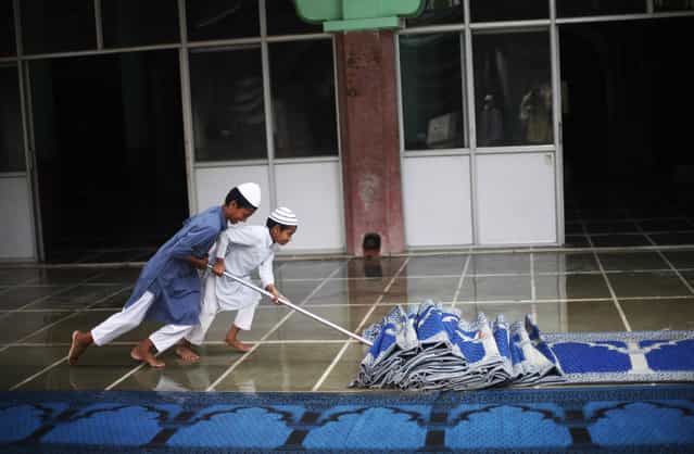 Young Indian Muslim boys mop the floor of a mosque which got wet during rains in New Delhi, India, Friday, June 14, 2013. The monsoon rains which usually hit India from June to September are crucial for farmers whose crops feed hundreds of millions of people. (Photo by Altaf Qadri/AP Photo)