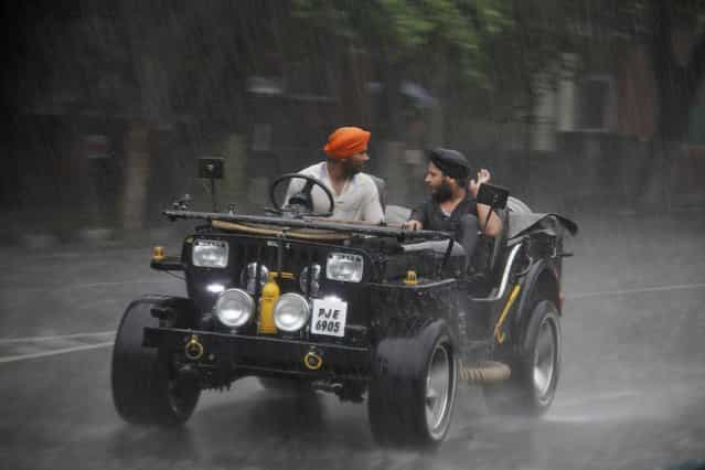 Sikh men ride a jeep during a heavy rain shower in the northern Indian city of Chandigarh June 13, 2013. India's weather office has forecast an average monsoon in the country in 2013. (Photo by Ajay Verma/Reuters)