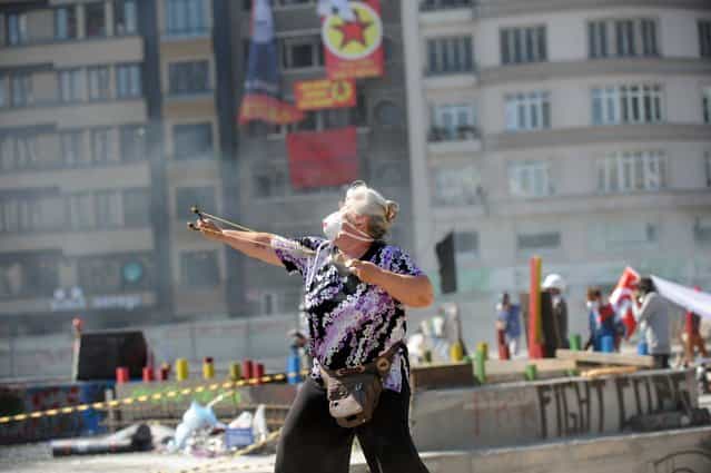 A protestors uses a slingshot against Turkish riot police on Taksim square on June 11, 2013. Riot police fired tear gas and rubber bullets to clear protesters from an Istanbul square on June 11 as Turkish Prime Minister Recep Tayyip Erdogan warned he would show [no more tolerance] for the unrelenting mass demonstrations against his Islamic-rooted government. Hundreds of police stormed the city's Taksim Square, the epicenter of nearly two weeks of unrest, in the early morning and brought bulldozers to clear the makeshift barriers erected by demonstrators after police pulled out of the area on June 1. (Photo by Bulent Kilic/AFP Photo)