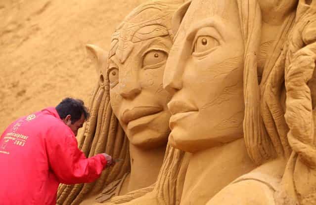 An artist works on two characters of the 'Avatar' movie, at the annual Sand Sculpture Festival, in coastal town Blankenberge, Belgium, on Wednesday, June 12, 2013. The festival has more than 40 professional sand artists from all around the world, and covers an area of over 4,000 square meters. (Photo by Yves Logghe/AP Photo)