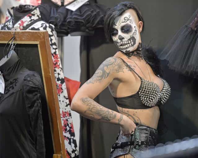 A woman with painted face checks her outfit in a mirror at the International Tattoo Convention in Dortmund, Germany, Friday, June 14, 2013. (Photo by Martin Meissner/AP Photo)
