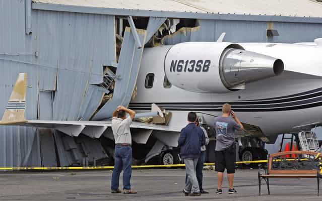 A jet sits on the runway after it struck a hanger at Chino Airport in Chino, Calif. on Friday June 14, 2013. Authorities say nobody was hurt when the small passenger jet with three people on board struck the hangar while taxiing. Federal Aviation Administration officials say the pilot apparently lost control during an engine test Thursday. The plane crashed halfway into the hangar at the Encore Jet Center. Firefighters shut off electricity because of a concern of leaking fuel. Four adjacent hangars and businesses within those hangars were evacuated. No injuries were reported. (Photo by Nick Ut/AP Photo)