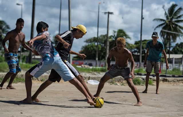 Boys play football in a shantytown of Olinda, about 18 km from Recife in northeastern Brazil, on June 18, 2013 as the FIFA Confederations Cup Brazil 2013 football tournament is being held in the country. The historic centre of Olinda is listed as an UNESCO World Heritage Site. (Photo by Yasuyoshi Chiba/AFP Photo)