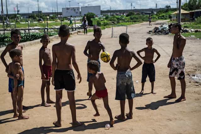 Boys start playing football in a shantytown of Olinda, about 18 km from Recife in northeastern Brazil, on June 18, 2013 as the FIFA Confederations Cup Brazil 2013 football tournament is being held in the country. The historic centre of Olinda is listed as an UNESCO World Heritage Site. (Photo by Yasuyoshi Chiba/AFP Photo)