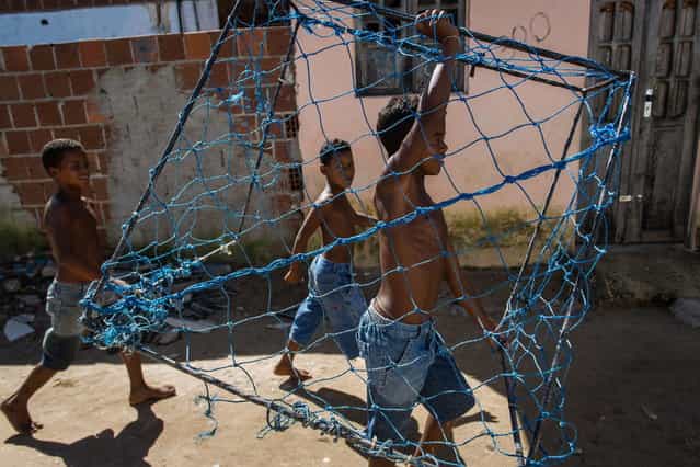 A boy carries a handmade goal as he heads to play football in a shantytown of Olinda, about 18 km from Recife in northeastern Brazil, on June 18, 2013 as the FIFA Confederations Cup Brazil 2013 football tournament is being held in the country. The historic centre of Olinda is listed as an UNESCO World Heritage Site. (Photo by Yasuyoshi Chiba/AFP Photo)