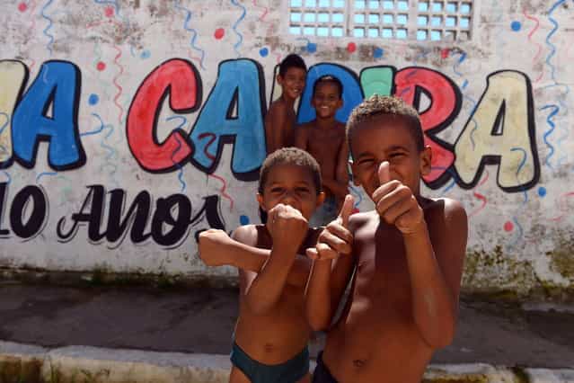 Boys pose for pictures in a shantytown of Olinda, about 18 km from Recife in northeastern Brazil, on June 18, 2013 during the FIFA Confederations Cup Brazil 2013 football tournament. The historic centre of Olinda is listed as an UNESCO World Heritage Site. (Photo by Vincenzo Pinto/AFP Photo)