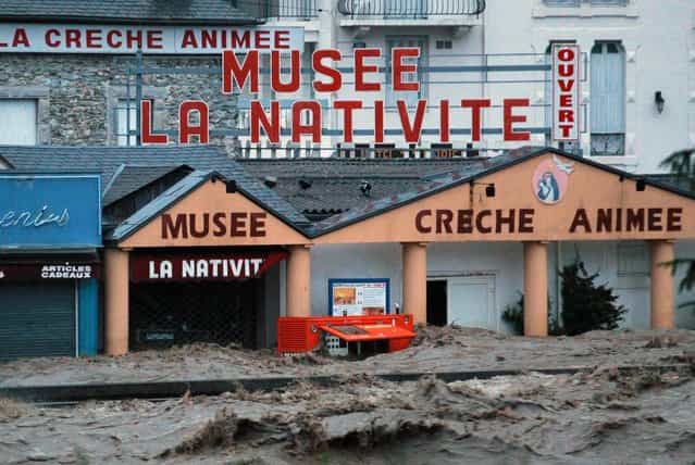 Shops in the center of Lourdes , southwestern France, under water Tuesday, June 18, 2013. French rescue services and police are evacuating hundreds of pilgrims from hotels threatened by floodwaters from a rain-swollen river in the Roman Catholic shrine town of Lourdes. (Photo by Bob Edme/AP Photo)
