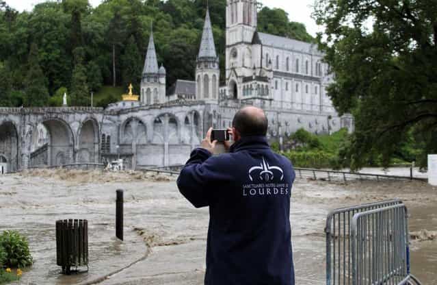 A guardian of Lourdes sanctuary takes photo of Lourdes sanctuary flooding in Lourdes, southwestern France, Tuesday, June 18, 2013. French rescue services and police are evacuating hundreds of pilgrims from hotels threatened by floodwaters from a rain-swollen river in the Roman Catholic shrine town of Lourdes. (Photo by Bob Edme/AP Photo)
