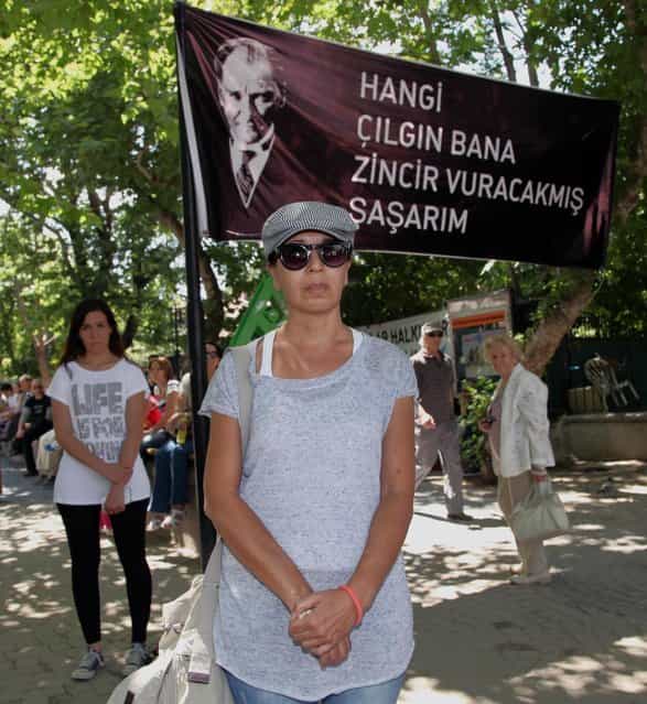 Turks stand in a silent protest in Kugulu Park in Ankara, Turkey, Wednesday, June 19, 2013. After weeks of sometimes-violent confrontation with police, Turkish protesters have found a new form of resistance: standing still and silent. The banner with an image of Turkey's founder Kemal Ataturk reads: [Which crazy person thinks they can put me in chains]. (Photo by Burhan Ozbilic/AP Photo)
