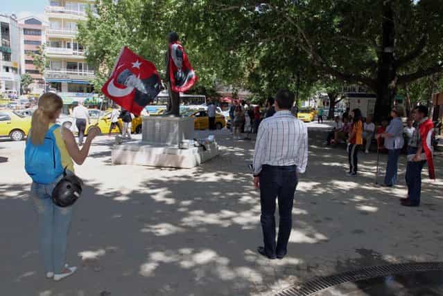 Turks, some of them wearing national flags with images of Turkey's founder Kemal Ataturk, stand in a silent protest in Kugulu Park in Ankara, Turkey, Wednesday, June 19, 2013. After weeks of sometimes-violent confrontation with police, Turkish protesters have found a new form of resistance: standing still and silent. (Photo by Burhan Ozbilic/AP Photo)