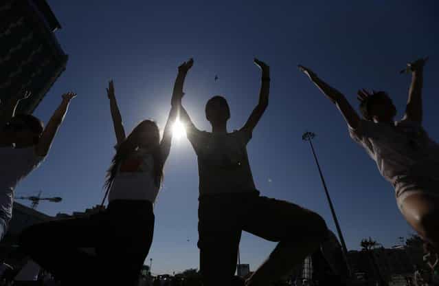 Young people silhouetted against the sun practice yoga during a silent protest at Taksim Square in, Istanbul, Turkey, Wednesday, June 19, 2013. After weeks of sometimes-violent confrontation with police, Turkish protesters have found a new form of resistance: standing still and silent. (Photo by Petr David Josek/AP Photo)