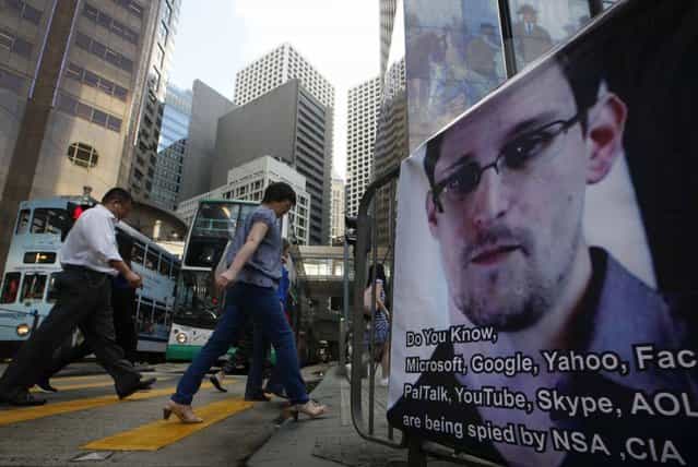 People walk past a banner supporting Edward Snowden, a former CIA employee who leaked top-secret documents about sweeping U.S. surveillance programs, at Central, Hong Kong's business district, Monday, June 17, 2013. Top officials from the Obama and Bush administrations say the government's newly exposed secret surveillance programs have been essential to disrupting terrorist plots and have not infringed on Americans' civil liberties. (Photo by AP Photo)