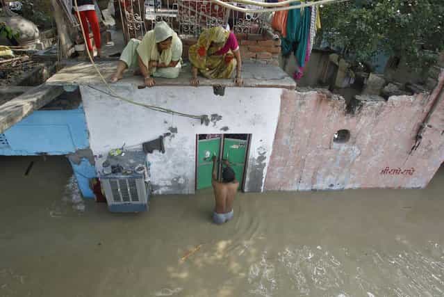 A man unlocks the door of his flooded house as other residents watch after a rise in the water level of river Yamuna in New Delhi, June 19, 2013. (Photo by Anindito Mukherjee/Reuters)