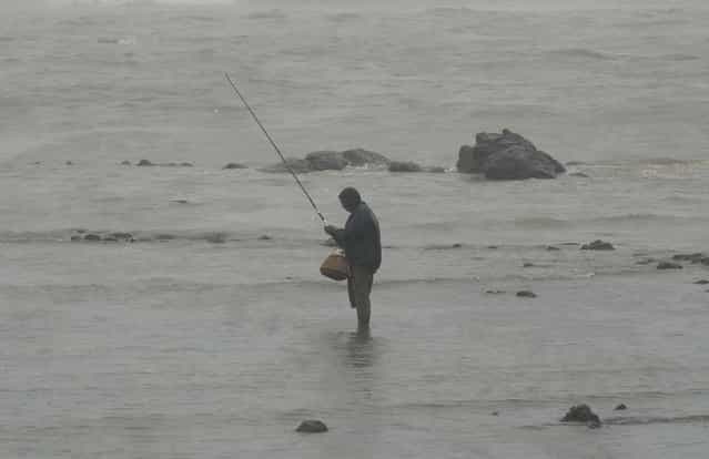 An Indian angler fishes on the sea front during heavy rain showers in Mumbai on June 18, 2013. The monsoon, which India's farming sector depends on, covers the subcontinent from June to September, usually bringing some flooding. But the heavy rains arrived early this year, catching many by surprise. The country has received 68 percent more rain than normal for this time of year, data from the India Meteorological Department shows. (Photo by Punit Paranjpe/AFP Photo)