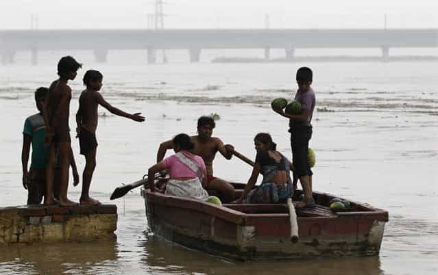 A man ferries his boat after retrieving floating watermelons from the flooded waters of river Yamuna in New Delhi June 18, 2013. The rains are at least twice as heavy as usual in northwest and central India as the June-September monsoon spreads north, covering the whole country a month faster than normal. (Photo by Anindito Mukherjee/Reuters)
