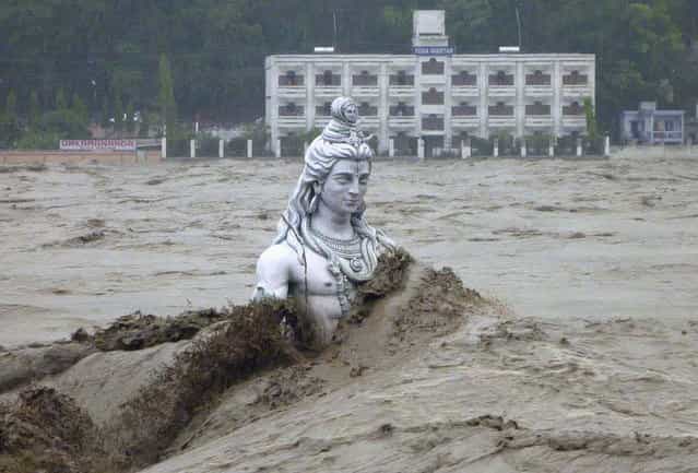 A submerged statue of the Hindu Lord Shiva stands amid the flooded waters of river Ganges at Rishikesh in the Himalayan state of Uttarakhand June 17, 2013. Early monsoon rains have swollen the Ganges, India's longest river, swept away houses, killed at least 60 people and left tens of thousands stranded, officials said on June 18, 2013. (Photo by Reuters/Stringer)