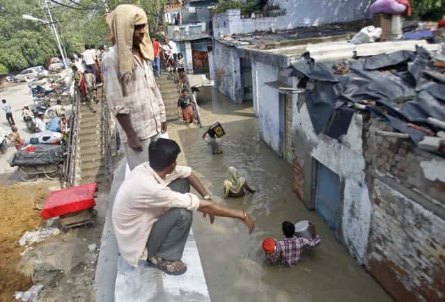 Residents carry their belongings through an alley flooded with the rising water level of river Yamuna after heavy monsoon rains in New Delhi June 19, 2013. The rains are at least twice as heavy as usual in northwest and central India as the June-September monsoon spreads north, covering the whole country a month faster than normal. (Photo by Anindito Mukherjee/Reuters)