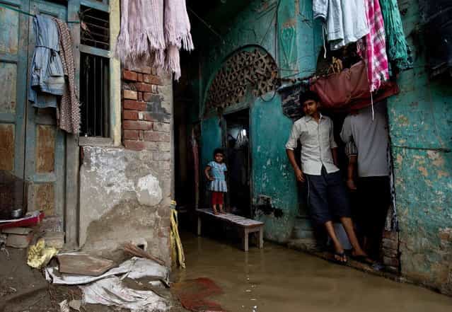An Indian girl stands on a bench as rising waters of the Yamuna river flowed into her home on the ghats in New Delhi on June 18, 2013. Monsoon rains have arrived early in northern India, leaving at least 64 people dead and thousands stranded, officials said June 18. (Photo by Manan Vatsyayana/AFP Photo)