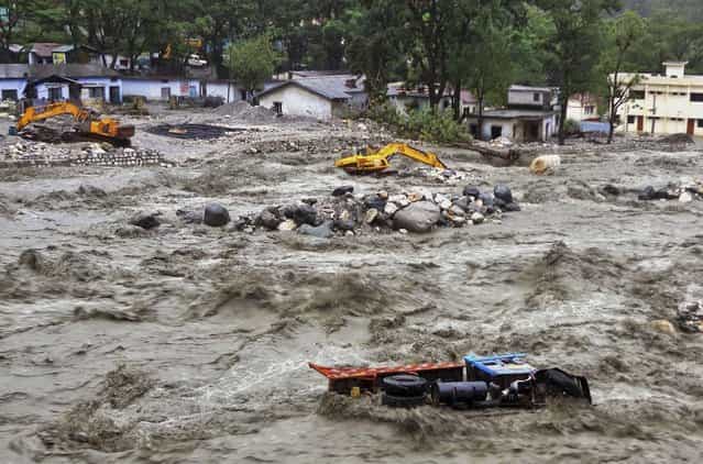 Bulldozer and other vehicles are drifted in a flooded river in Uttarkashi district, India, Monday, June 17, 2013. Torrential rain and floods washed away buildings and roads, killing at least 23 people on Monday in the northern Indian state of Uttarakhand, officials said Monday. (AP Photo)