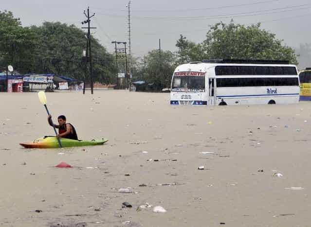 A man rows past a bus partly submerged in flood water in Rishikesh, in the northern Indian state of Uttarakhand, India, Tuesday, June 18, 2013. Monsoon torrential rains have cause havoc in northern India leading to flash floods, cloudbursts and landslides as the death toll continues to climb and more than 1,000 pilgrims bound for Himalayan shrines remain stranded. (Photo by AP Photo)