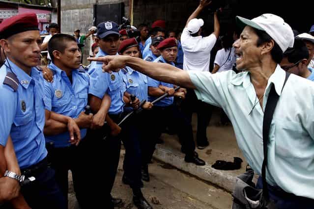 A member of the National Elderly Unit shouts slogans in front of a police line during a protest near the Nicaraguan Social Security building in Managua, on June 19, 2013. Hundreds of senior citizens are demanding the government give them a partial pension as they did not qualify for a full pension because they were unable to pay into the system for the required time, due to the instability of the country resulting from war and natural disasters. (Photo by Esteban Felix/Associated Press)