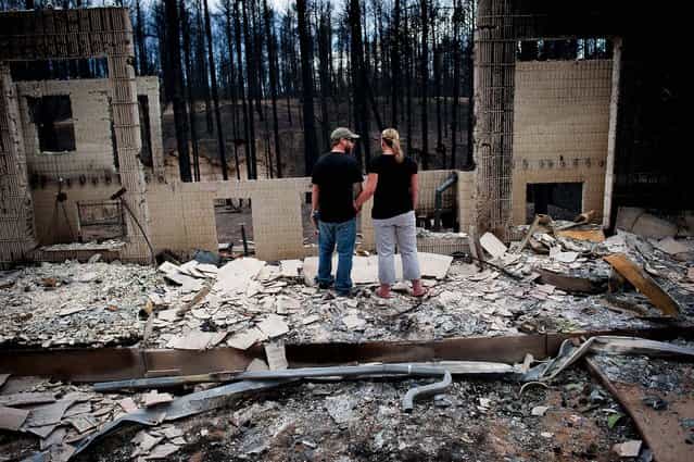 Jeremy and Kelly Beach look into the remains of their home off Ravine Drive in Colorado Springs, on June 18, 2013. As the West battles one catastrophic wildfire after another, the federal government is spending less and less on its main program for preventing blazes in the first place. (Photo by Michael Ciaglo/The Colorado Springs Gazette)