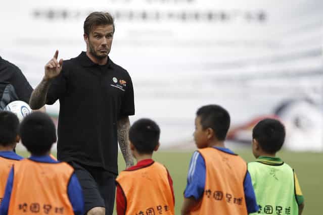 Former England soccer team captain David Beckham explains to primary school students how to play soccer in Nanjing, Jiangsu province June 18, 2013. According to local media, Beckham arrived in the China on Monday to start his second trip as China's soccer envoy. (Photo by Aly Song/Reuters)