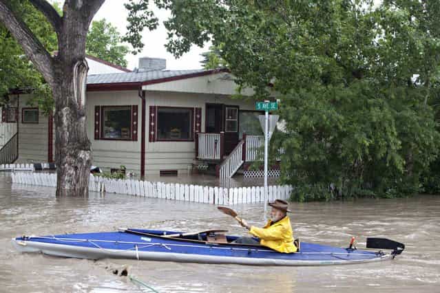 A kayaker paddles down a flooded street in High River, Alberta on Thursday, June 20, 2013 after the Highwood River overflowed its banks. Calgary city officials say as many as 100,000 people could be forced from their homes due to heavy flooding in western Canada, while mudslides have forced the closure of the Trans-Canada Highway around the mountain resort towns of Banff and Canmore. (Photo by Jordan Verlage/AP Photo/The Canadian Press)