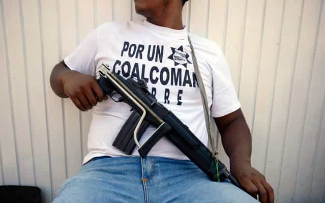 An armed man - member of a vigilante group – keeps watch in Coalcoman community, in Michoacan State, Mexico, on May 22, 2013. Vigilante groups, calling themselves [community police], have sprung up this year in western and southern Mexican towns, in an effort to combat drug-related violence. (Photo by Alfredo Estrella/AFP Photo)