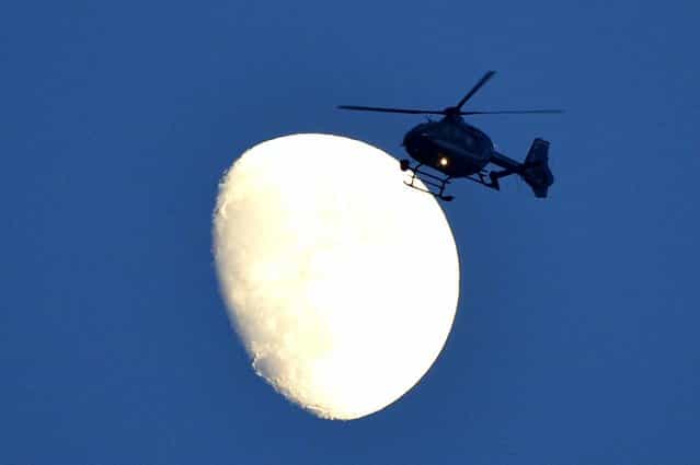 A helicopter flies in front of the moon at the airport in Berlin on June 19, 2013 ahead of the departure of US President Barack Obama. Obama said Russian and US nuclear weapons should be slashed by up to a third in a keynote speech in front of Berlin's iconic Brandenburg Gate in which he called for a world of [peace and justice]. (Photo by Odd Andersenodd Andersen/AFP Photo)
