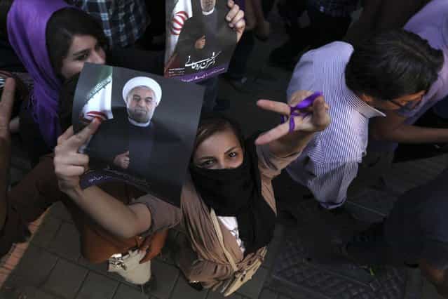 A female supporter of Iranian presidential candidate Hasan Rowhani, flashes a victory sign as she holds his poster during a celebration gathering in Tehran, Iran, Saturday, June 15, 2013. Moderate cleric Hasan Rowhani was declared the winner of Iran's presidential vote on Saturday after gaining support among many reform-minded Iranians looking to claw back a bit of ground after years of crackdowns. (Photo by Vahid Salemi/AP Photo)