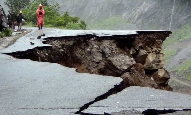 People walk on a road which caved in after incessant rains on Rishikesh-Mana highway in the northern Indian state of Uttarakhand, on June 17, 2013. Torrential rain and floods washed away buildings and roads, killing at least 23 people in the state, officials said Monday. (Photo by Associated Press)