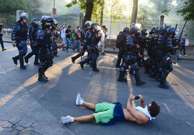 Riot police are seen during clashes with protestors outside of Maracana stadium during the FIFA 2013 Confederation Cup football match between Mexico and Italy in Rio de Janeiro, Brazil on June 16, 2013. Police deployed tear gas and rubber bullets to disperse around 3,000 demonstrators attempting to enter the stadium in protest at the vast sums of money spent on the organisation of the tournament and next year's World Cup, which Brazil is also hosting. (Photo by Tasso Marcelo/AFP Photo)