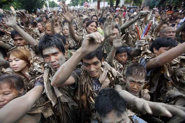 People, covered with mud and dried banana leaves, raise their hands for blessing as they attend a mass celebrating the feast day of the Catholic patron Saint John the Baptist in the village of Bibiclat, Nueva Ecija, north of Manila, June 24, 2013. Hundreds of devotees took part in this annual religious tradition, which has been held in the village since 1945. (Photo by Cheryl Ravelo/Reuters)
