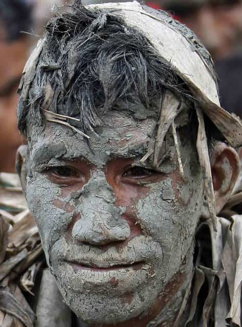A man, covered with mud and dried banana leaves, attends a mass celebrating the feast day of the Catholic patron Saint John the Baptist in the village of Bibiclat, Nueva Ecija, north of Manila, June 24, 2013. Hundreds of devotees took part in this annual religious tradition, which has been held in the village since 1945. (Photo by Cheryl Ravelo/Reuters)