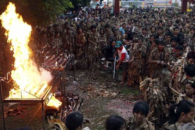 Residents, covered with mud and dried banana leaves, move away from the fire during a mass celebrating the feast day of the Catholic patron Saint John the Baptist in the village of Bibiclat, Nueva Ecija, north of Manila, June 24, 2013. Hundreds of devotees took part in this annual religious tradition, which has been held in the village since 1945. (Photo by Cheryl Ravelo/Reuters)