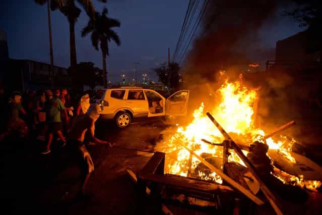 Protesters push a car towards a police line to set it on fire during a demonstration in Belo Horizonte, Brazil, Wednesday, June 26, 2013. The wave of protests that hit Brazil in mid-June began as opposition to transportation fare hikes, then expanded to a laundry list of causes including anger at high taxes, poor services and high World Cup spending, before coalescing around the issue of rampant government corruption. (Photo by Victor R. Caivano/AP Photo)