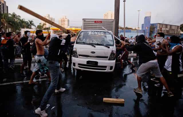Protesters destroy a van during a demonstration in Belo Horizonte, Brazil, Wednesday, June 26, 2013. Brazilian protesters and police clashed Wednesday near a stadium hosting a Confederations Cup soccer match, as thousands of demonstrators trying to march on the site were met by tear gas and rubber bullets. (Photo by Victor R. Caivano/AP Photo)