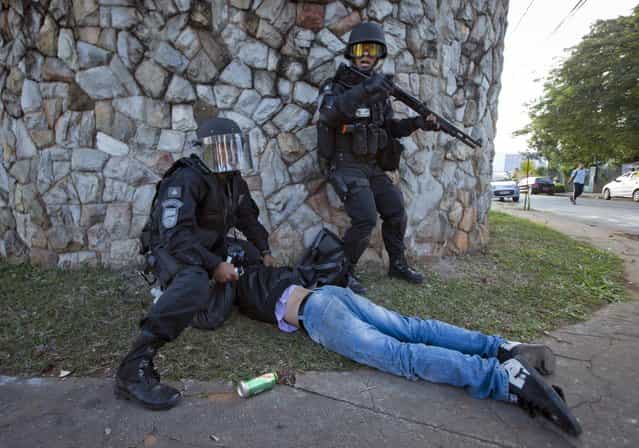 Riot police detain a man during a demonstration in Belo Horizonte, Brazil, Wednesday, June 26, 2013. Brazilian anti-government protesters in part angered by the billions spent in World Cup preparations and police clashed Wednesday near the stadium hosting a Confederations Cup football match, with tens of thousands of demonstrators trying to march on the site confronting police firing tear gas and rubber bullets. (Photo by Victor R. Caivano/AP Photo)