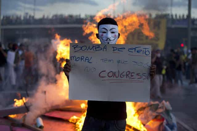 A protester holds a sign that reads in Portugues [throw tear gas to the congress] during a demonstration in Belo Horizonte, Brazil, Wednesday, June 26, 2013. Brazilian anti-government protesters in part angered by the billions spent in World Cup preparations and police clashed Wednesday near the stadium hosting a Confederations Cup football match, with tens of thousands of demonstrators trying to march on the site confronting police firing tear gas and rubber bullets. (Photo by Victor R. Caivano/AP Photo)