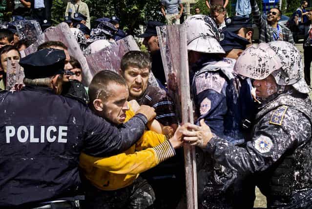 Police, who were splashed with paint, scuffle with hard line opposition members in Pristina, Kosovo, protesting an agreement by lawmakers to normalize relations with Serbia, on June 27, 2013. (Photo by Visar Kryeziu/Associated Press)