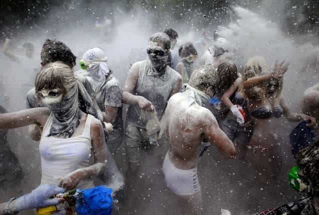 People throw flour over each other in Kiev, Ukraine during a gathering on a beach of the Dnieper River, on June 22, 2013. (Photo by Sergei Chuzavkov/Associated Press)