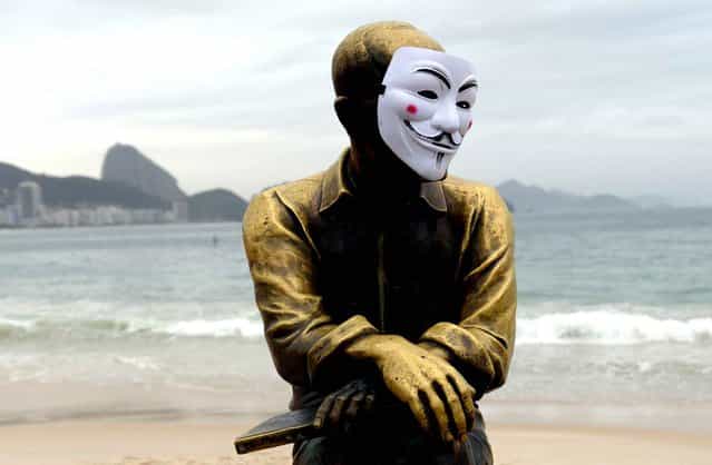 The statue of Brazilian poet Carlos Drummond de Andrade on Copacabana Beach with a Guy Fawkes mask, on June 23, 2013. (Photo by Yasuyoshi Chiba/AFP Photo)