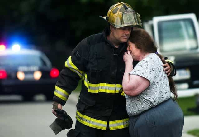 Grand Blanc firefighter Brad Hutchison consoles Wanda McCann after he informed her that her friend and neighbor was killed in a house fire Tuesday morning in Grand Blanc Township, Michigan, on June 25, 2013. Police and firefighters tried to rescue a woman in her early 60s, but were unable to enter the home because of heavy smoke. It is the township's first fatal fire in about seven or eight years, said fire chief Jim Harmes. (Photo by Jake May/The Flint Journal)