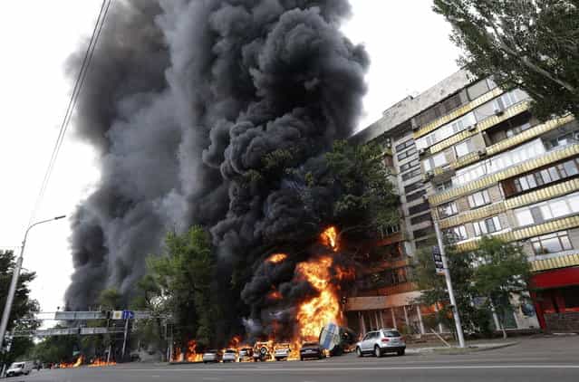 Burning vehicles are seen at the site of a fire in Almaty June 27, 2013. A 16-ton tank truck rolled over after an accident, setting parked cars and a nearby apartment building ablaze, Emergency Ministry reported. (Photo by Sergey Khodanov/Reuters)