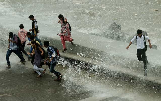 Indian pedestrians run from water splashing over a sea wall in Mumbai on June 24, 2013. The monsoon, which covers the subcontinent from June to September, usually brings some flooding. But the heavy rains arrived early this year, catching many by surprise and exposing a lack of preparedness. (Photo by Punit Paranjpe/AFP Photo)